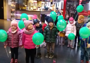 Widok na dzieci trzymające w rękach zielone baloniki.